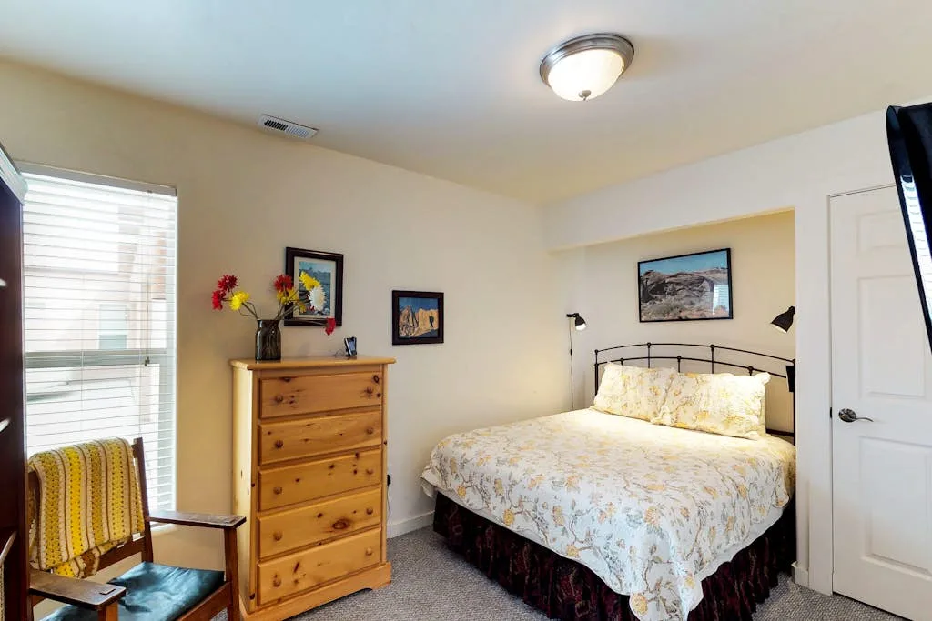 Un dormitorio con una cama, una cómoda de madera y una ventana con persianas.