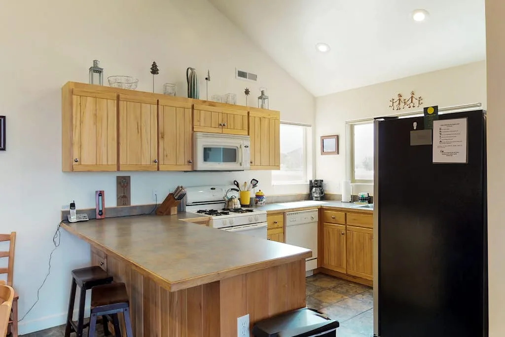 Una cocina con gabinetes de madera, una isla central y un refrigerador negro.