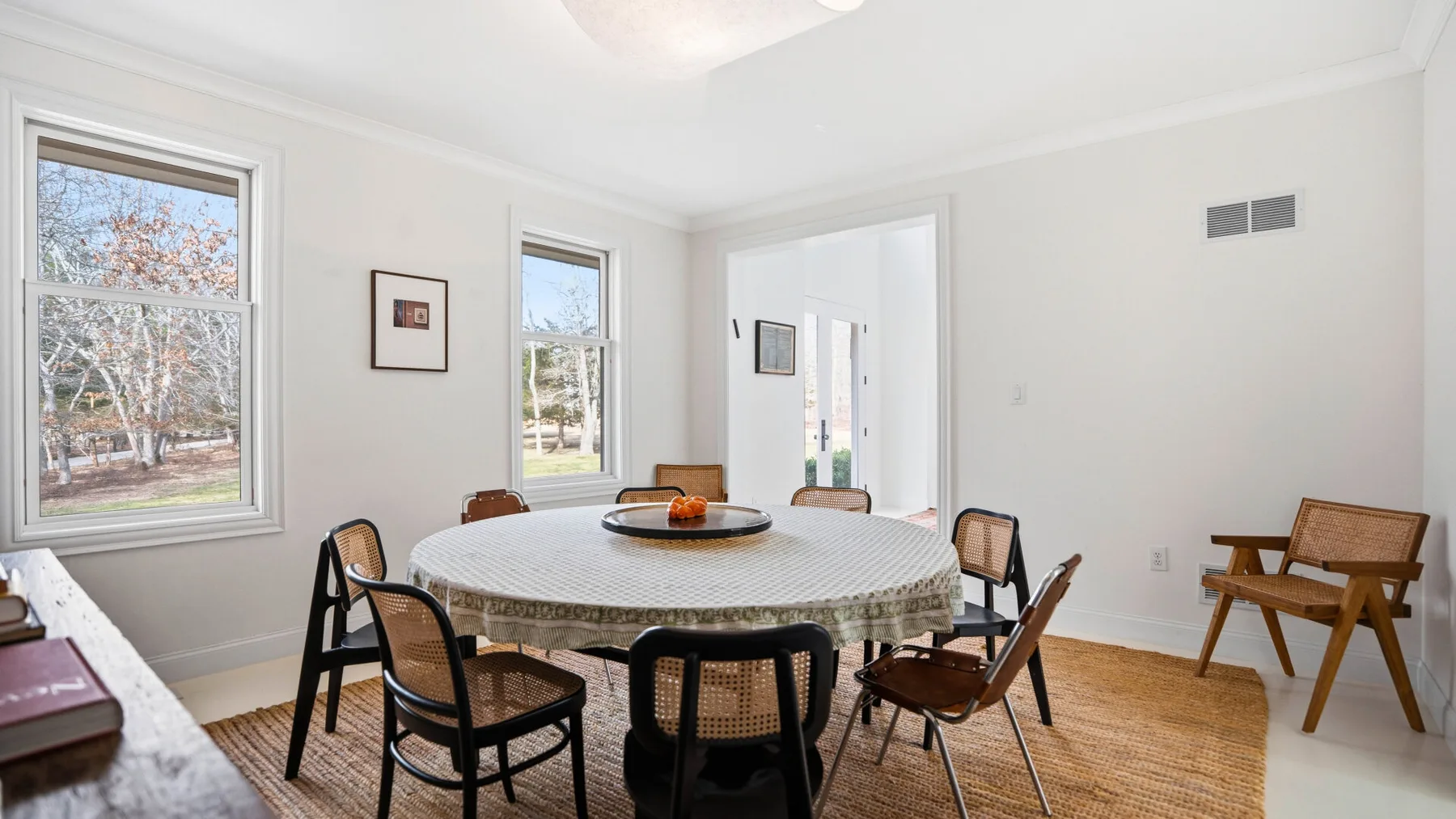 Un comedor luminoso con una mesa redonda y ventanas con vista a los árboles.