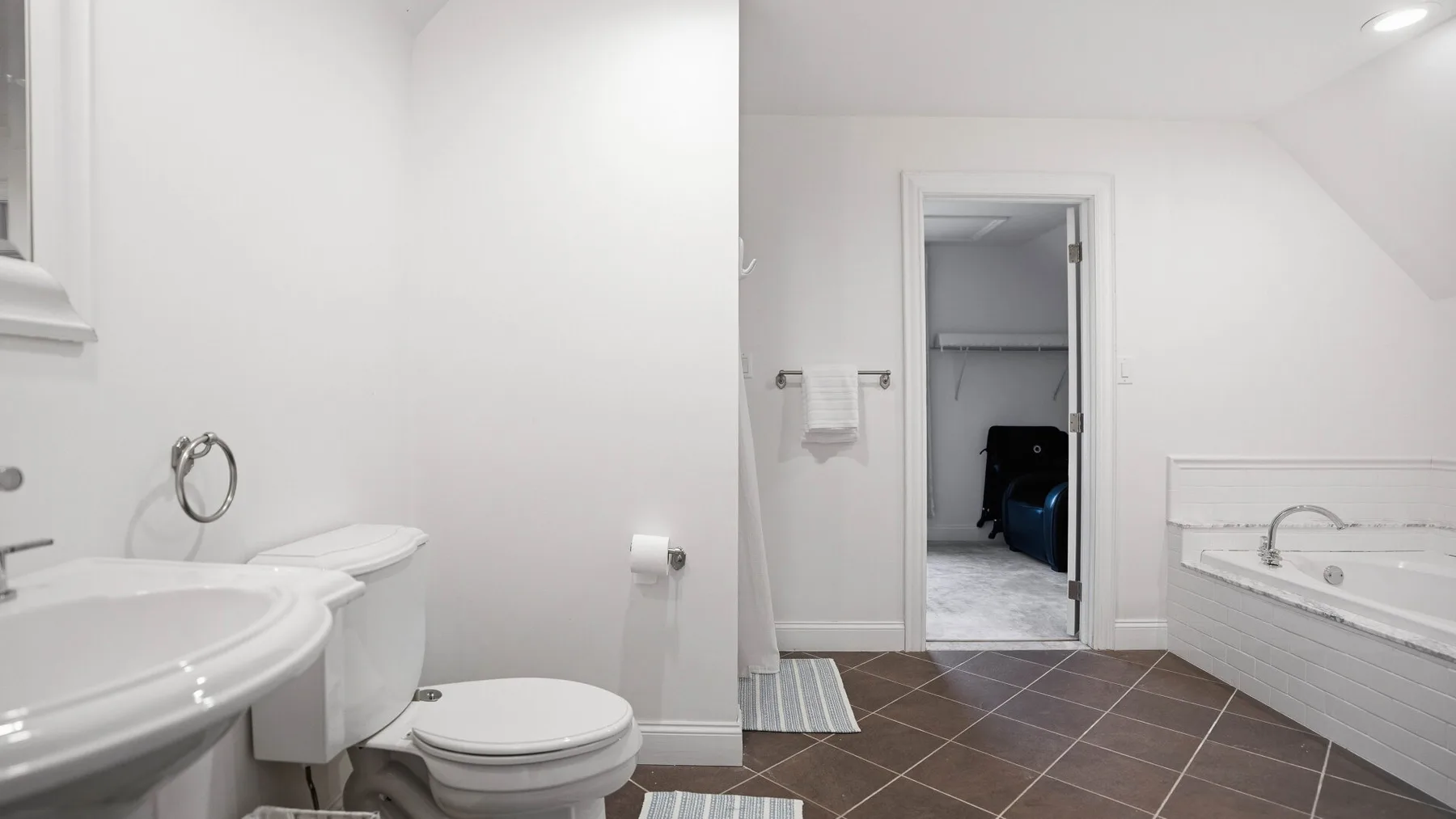 Un baño luminoso con lavabo, inodoro y una puerta abierta.