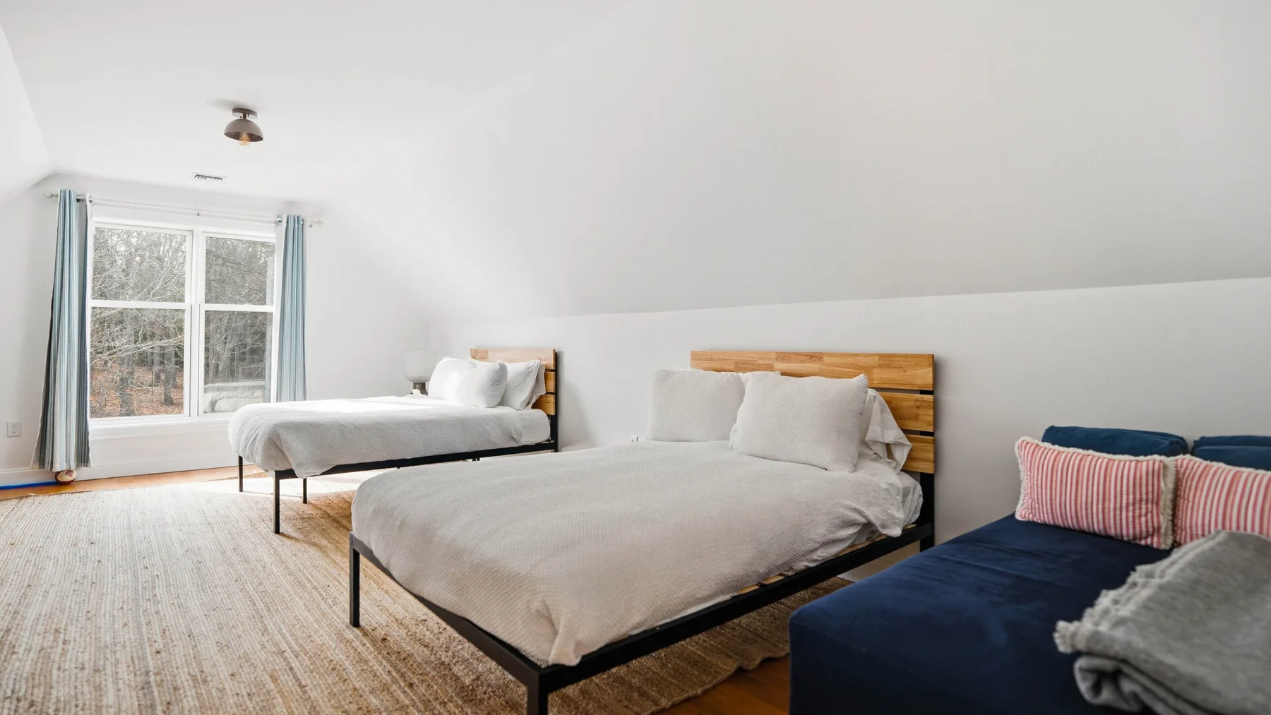 Un dormitorio luminoso con dos camas y una ventana grande.