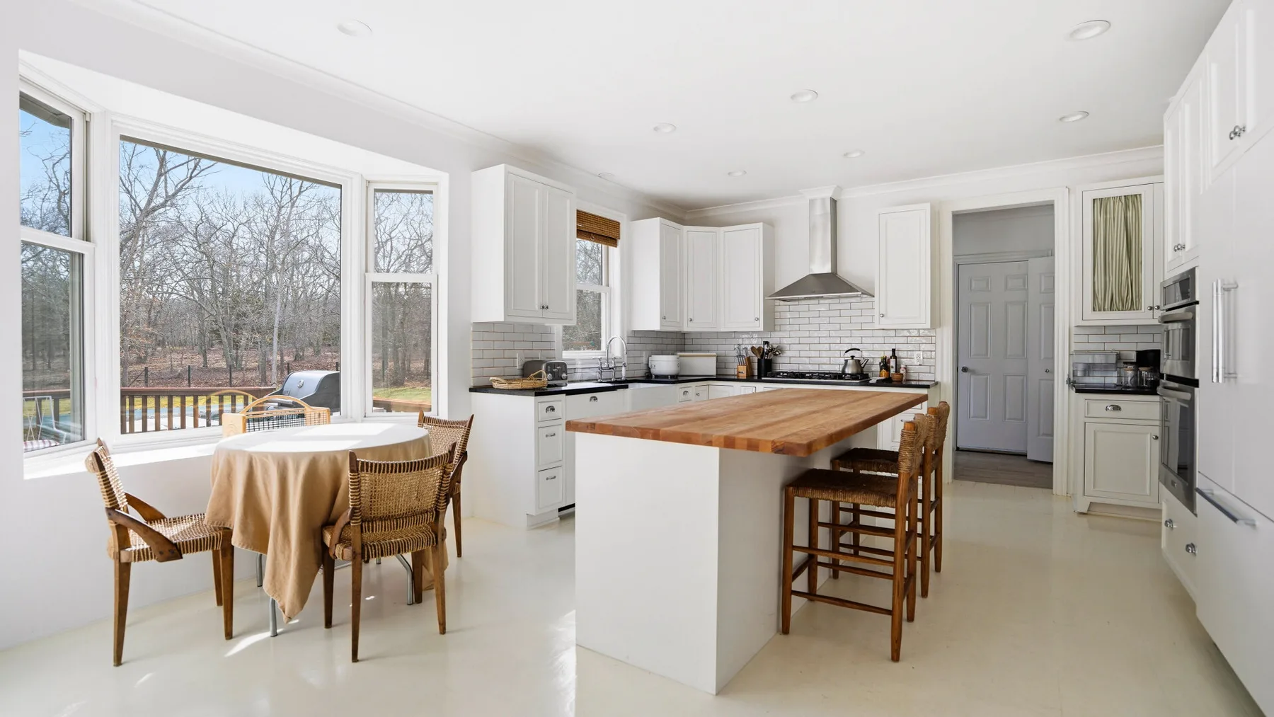 Una cocina luminosa con una isla central y una mesa de comedor junto a grandes ventanas.
