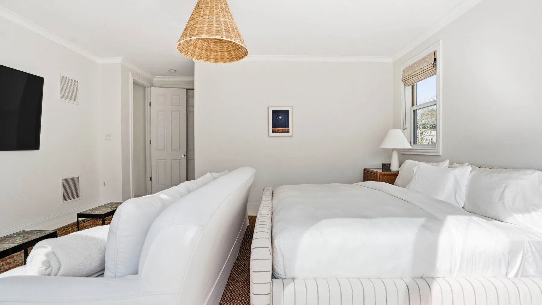 Un dormitorio luminoso con dos camas, ropa de cama blanca y una ventana.