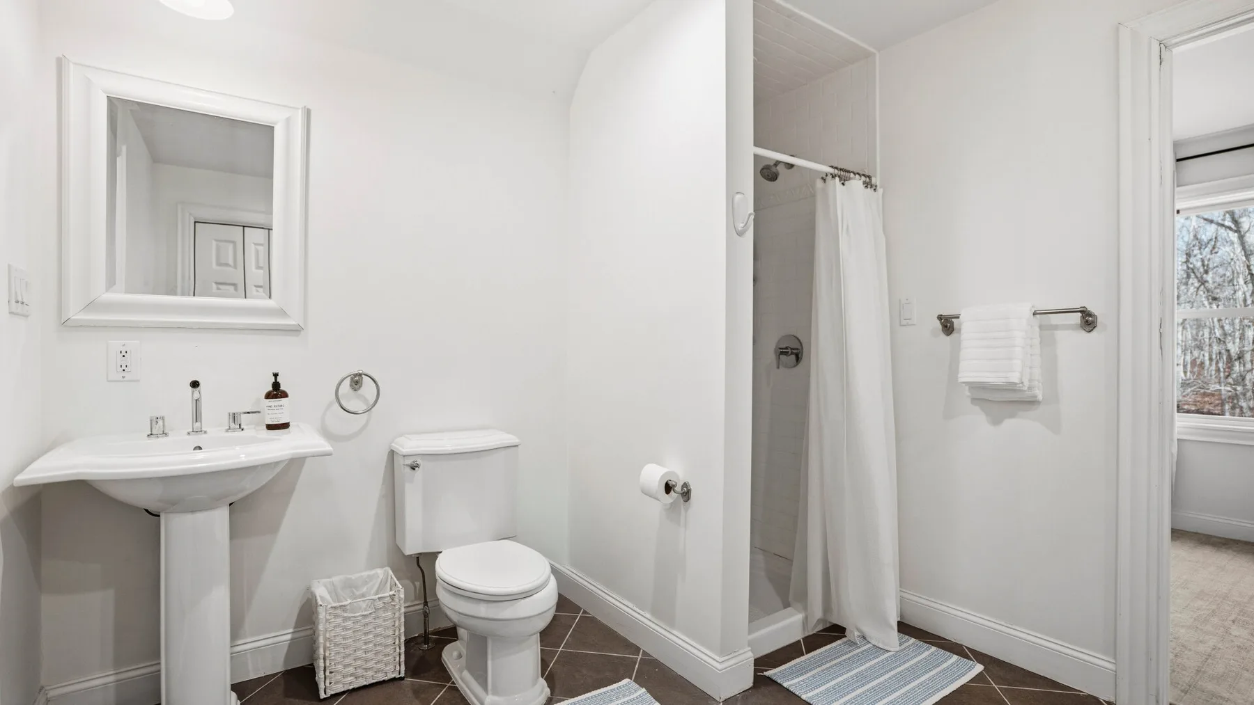 Un baño luminoso con lavabo, inodoro y ducha con cortina.