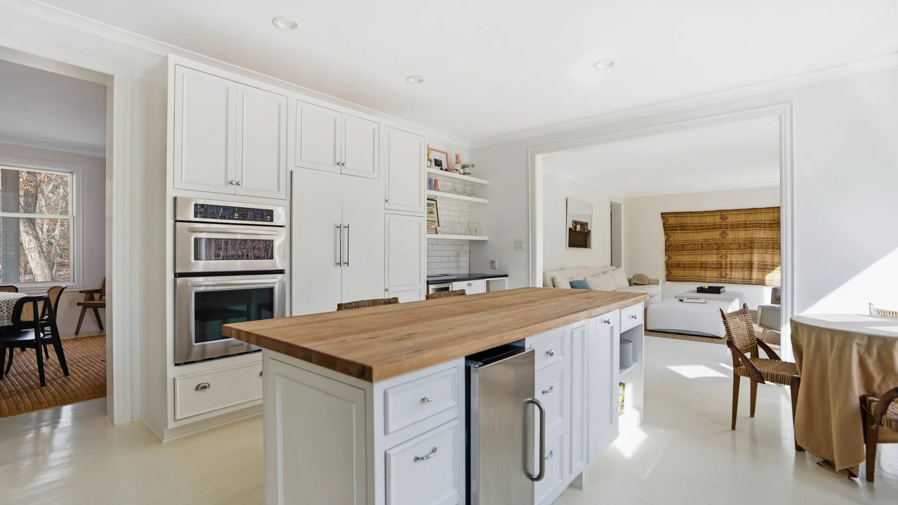 Una cocina luminosa con una gran isla central y armarios blancos.
