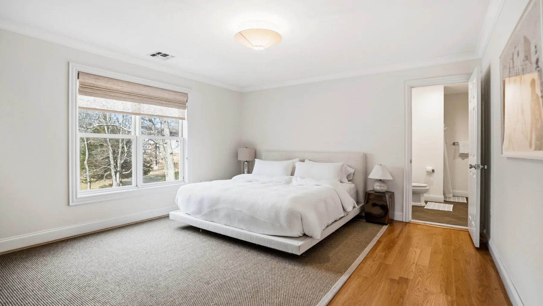 Un dormitorio luminoso con una cama grande junto a una ventana.