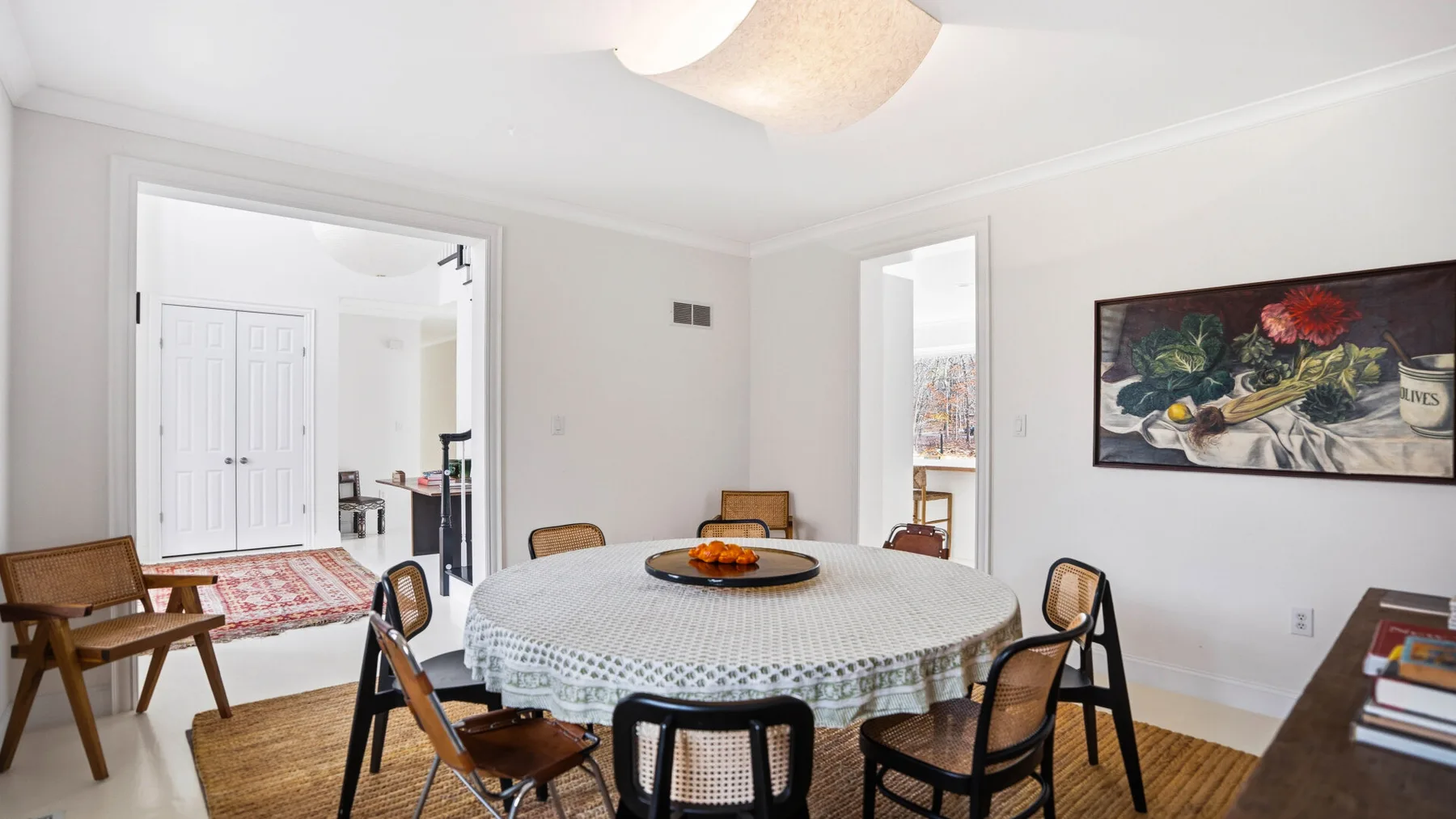 Un comedor con una mesa redonda, sillas y un cuadro en la pared.