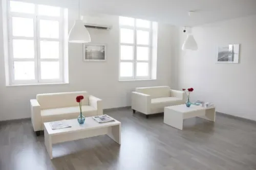 A bright sitting area with two seating arrangements and low tables.