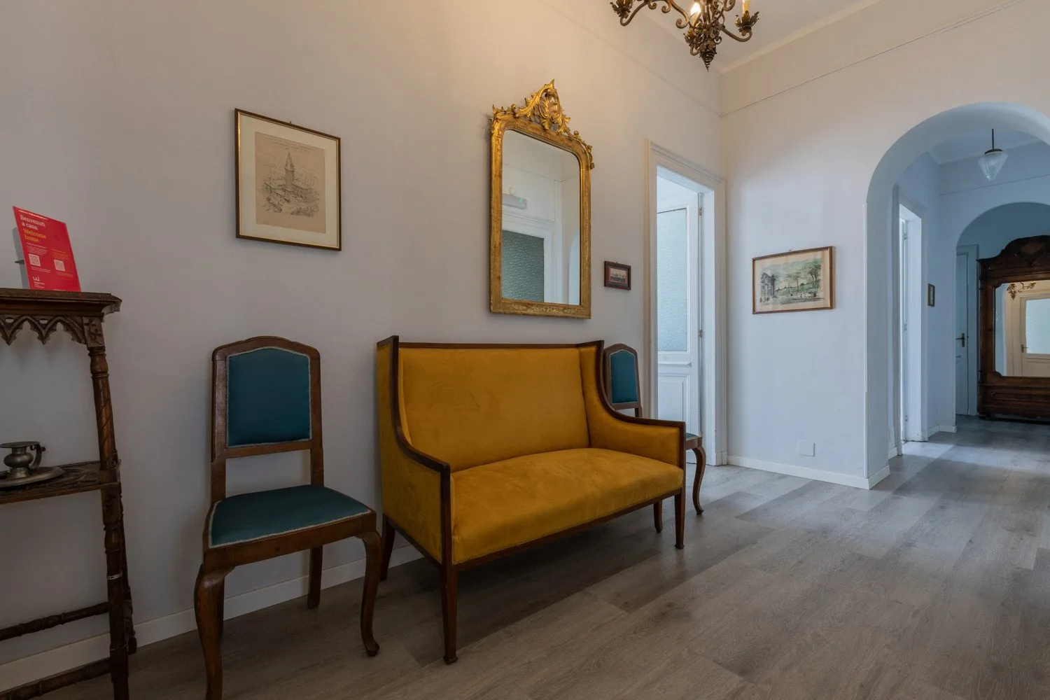 Una sala de estar con un sofá amarillo mostaza, sillas y un espejo enmarcado.