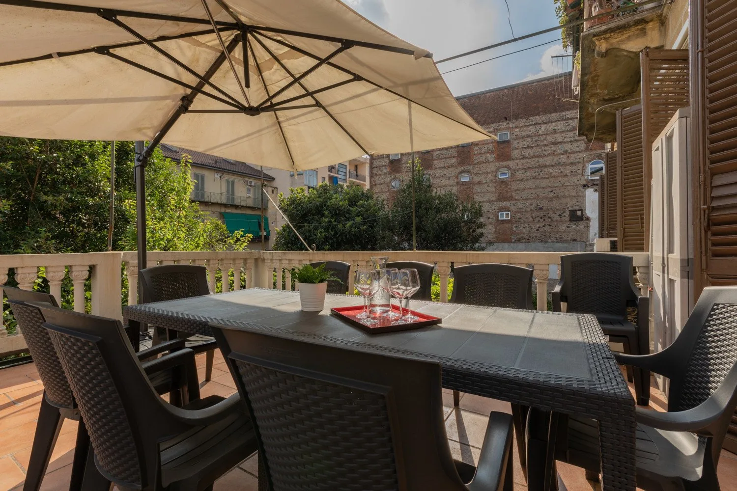 Un patio comedor al aire libre con una mesa y sillas bajo una sombrilla grande.