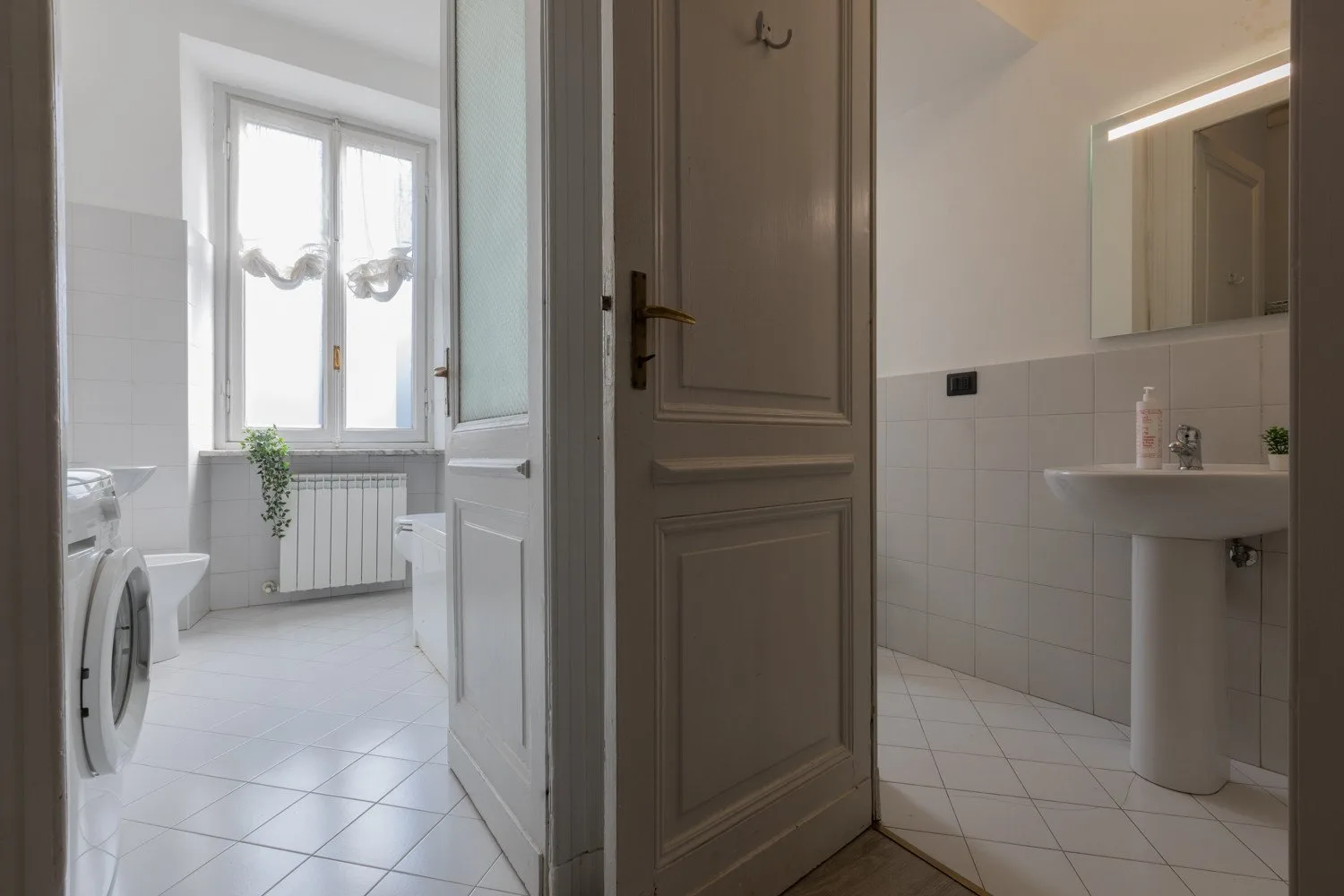 Un baño con azulejos, lavabo, espejo y lavadora.