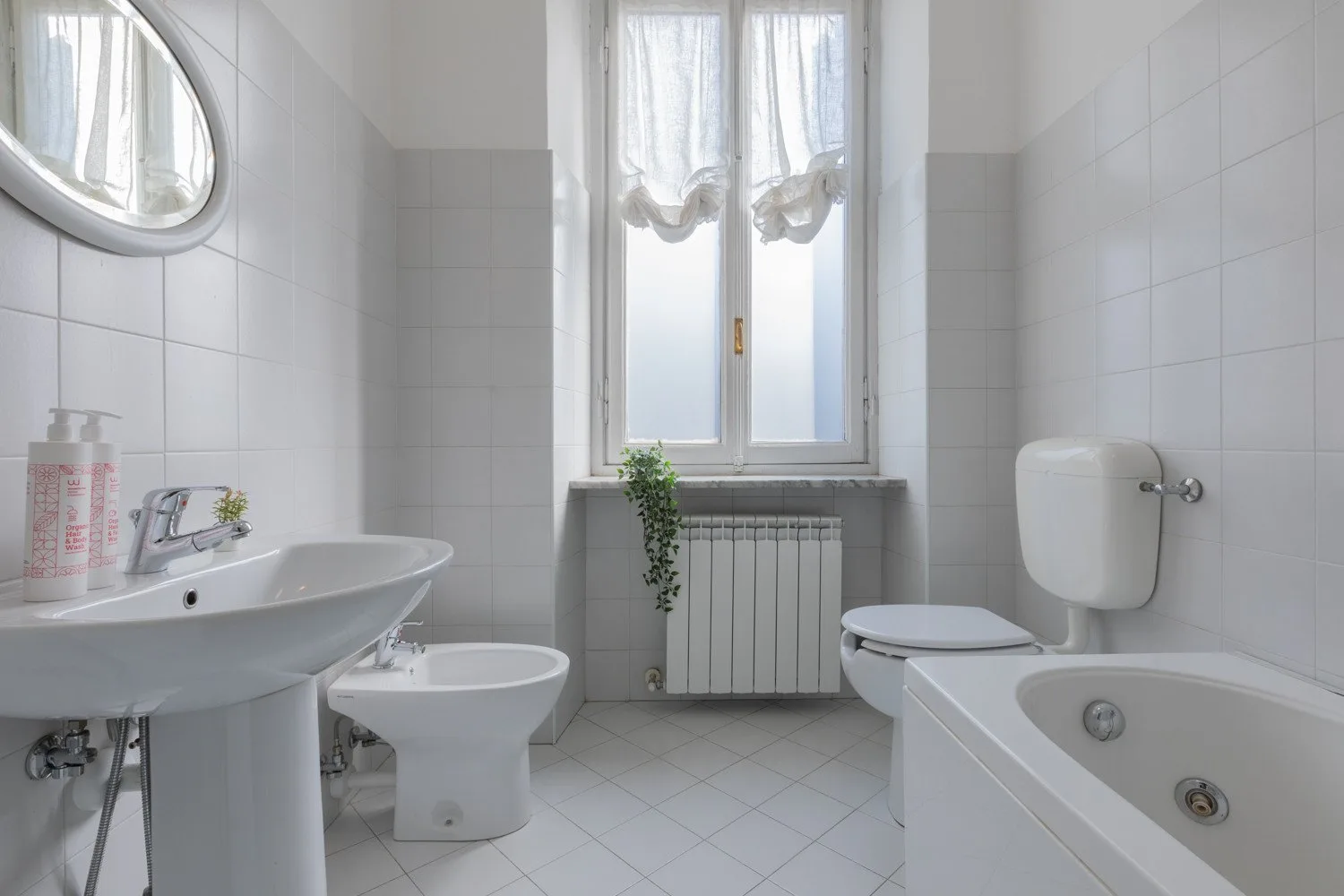 Un baño con azulejos, lavabo, inodoro, bañera y ventana.