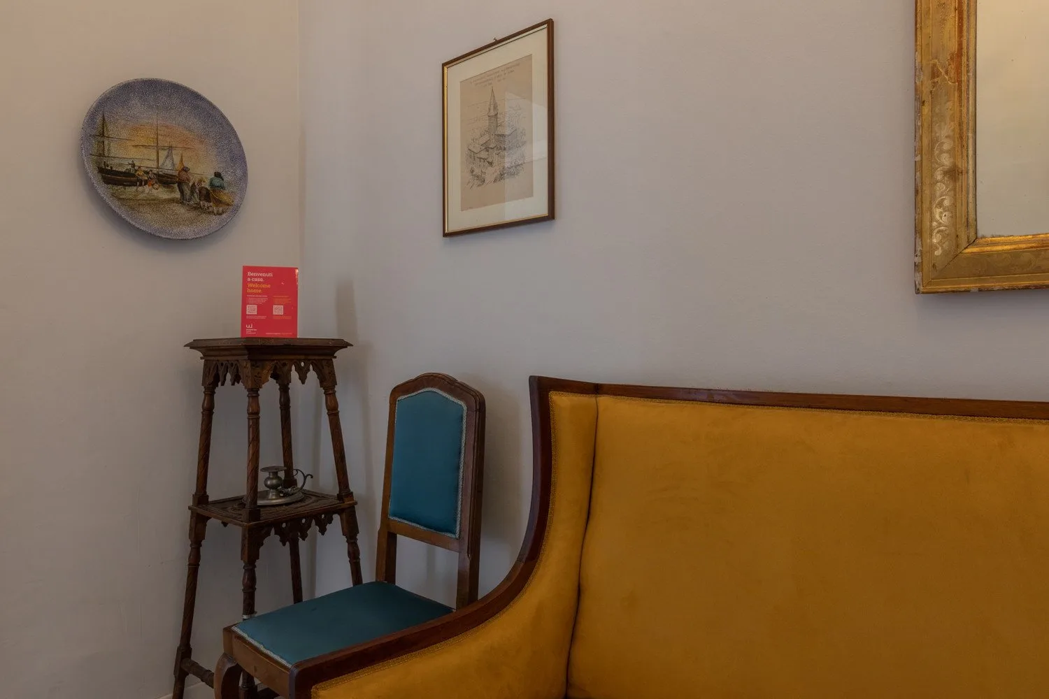 Una zona de estar con un sofá amarillo mostaza y una silla tapizada azul.