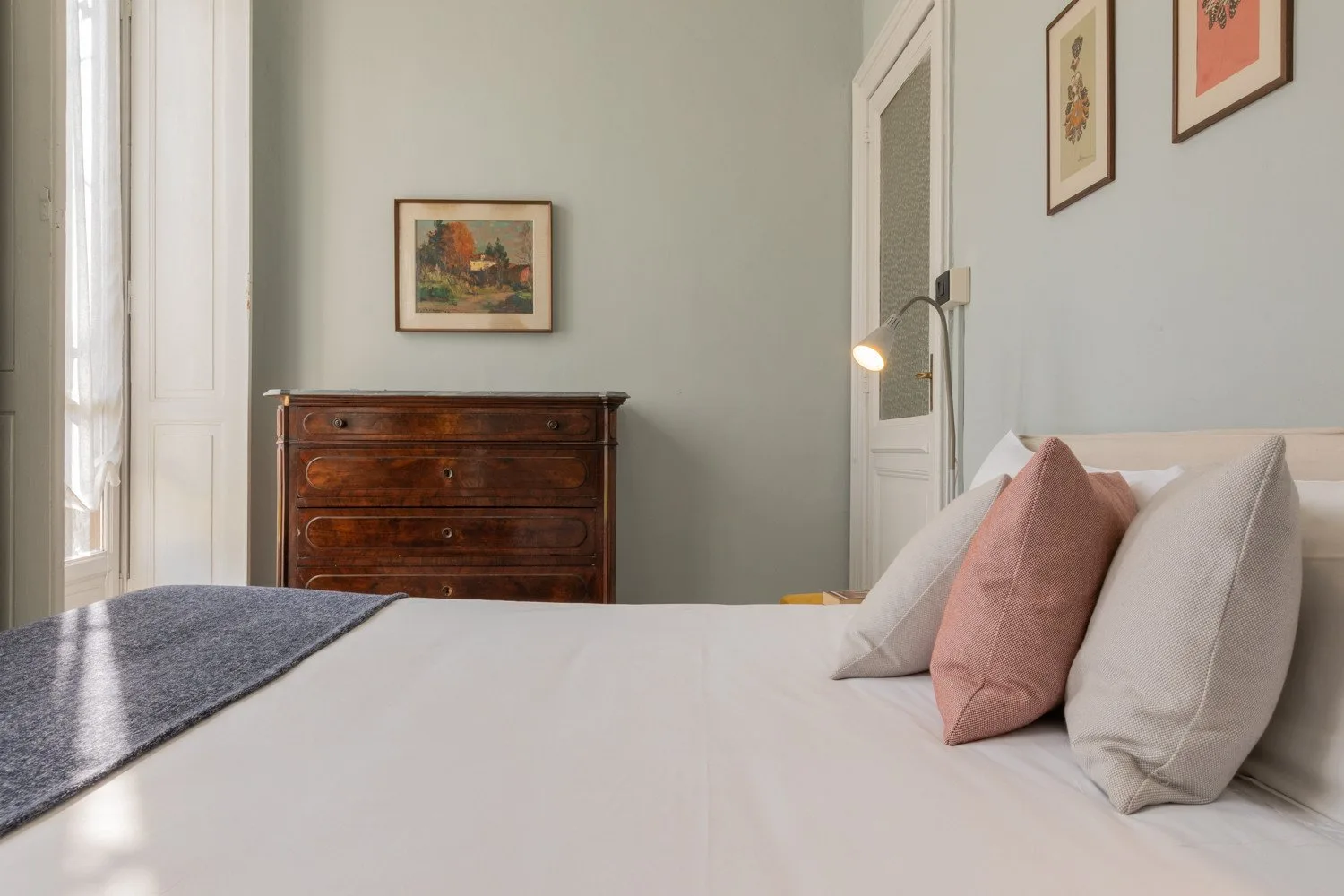 Un dormitorio con una cama bien tendida y una cómoda de madera.