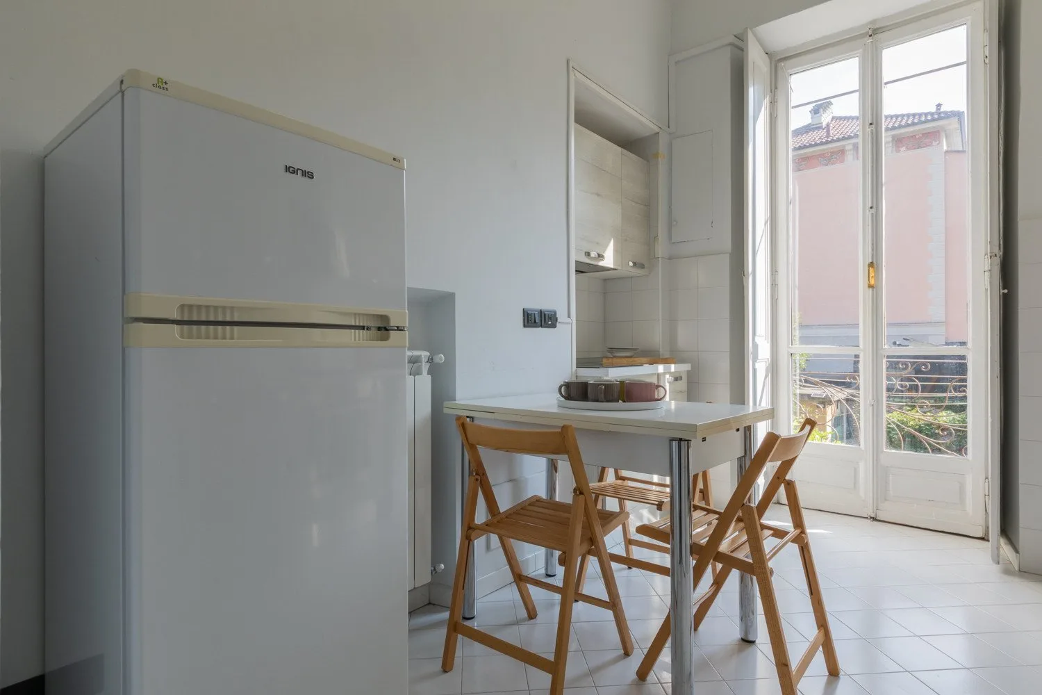 Un comedor luminoso con una mesa y sillas junto a unas puertas acristaladas altas.