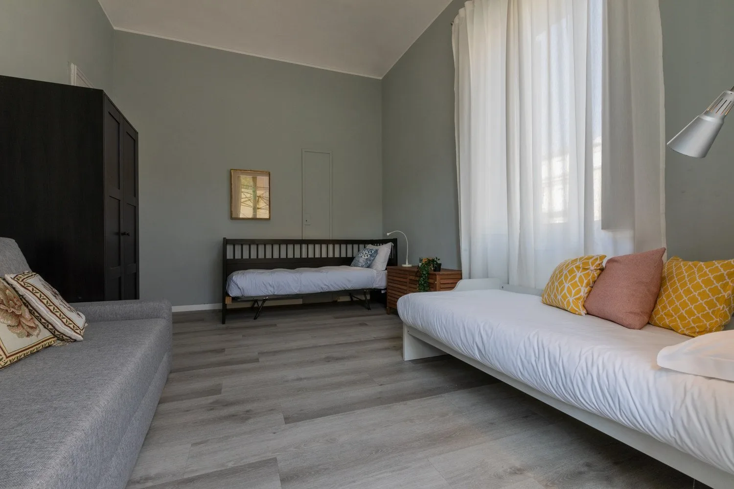 Un dormitorio con una cama, un diván y una gran ventana con cortinas.