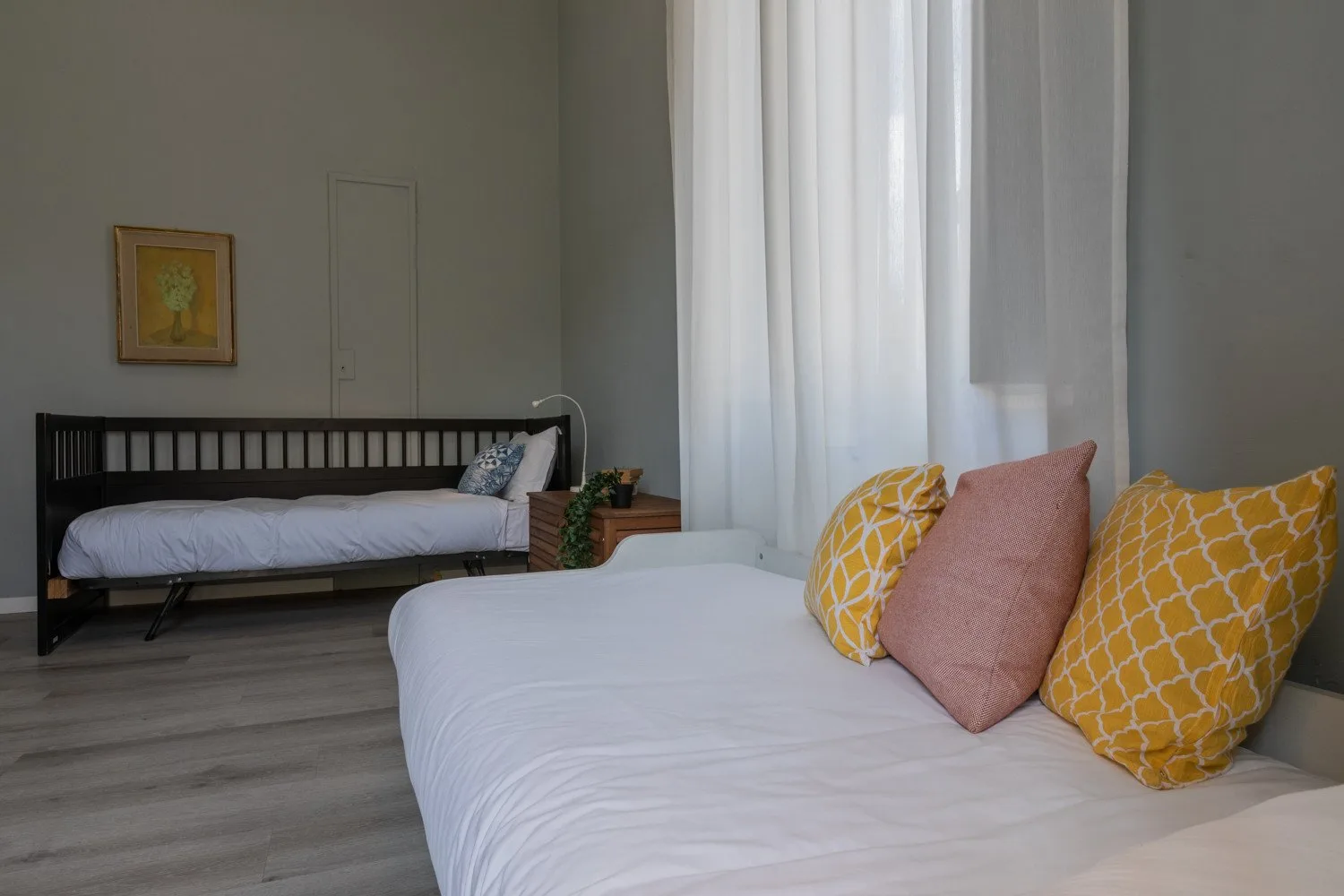 Un dormitorio con una cama en primer plano y un diván junto a la ventana.