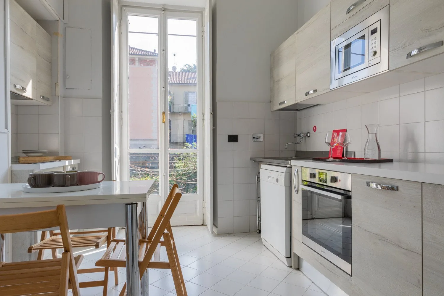 Una cocina luminosa con electrodomésticos integrados y una mesa junto a la ventana.