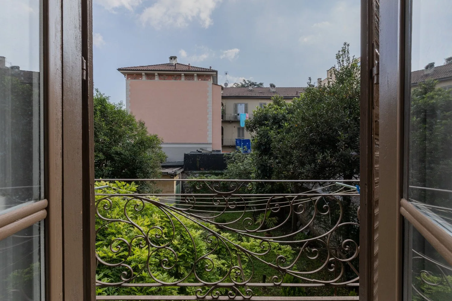 Una ventana abierta da a árboles frondosos y edificios residenciales cercanos.