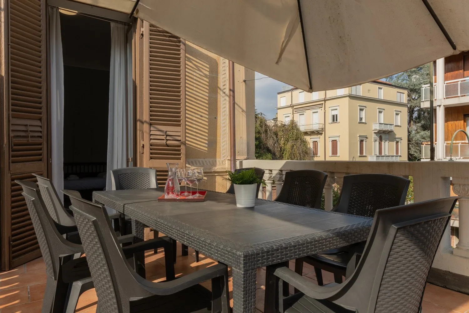 Un comedor exterior a la sombra tiene una mesa larga y varias sillas.