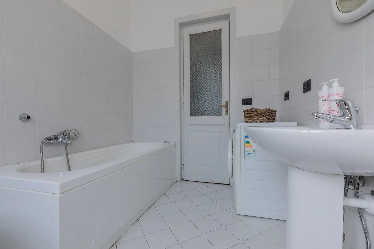 Un baño con azulejos, bañera, lavabo y una puerta.