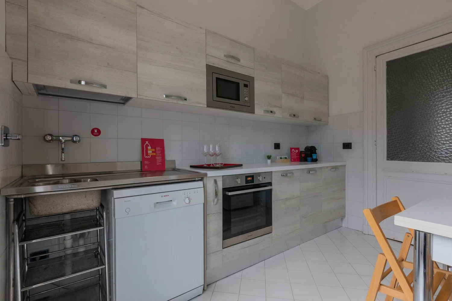 Una cocina compacta con armarios claros, electrodomésticos integrados y una pequeña mesa de comedor.