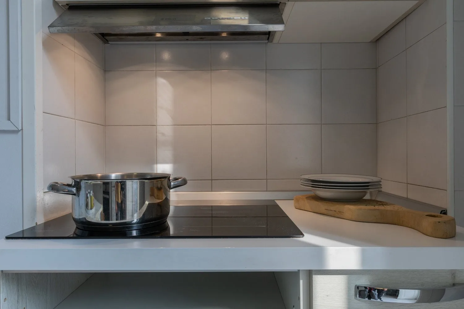 Una placa de cocina con una olla metálica y una tabla de cortar.