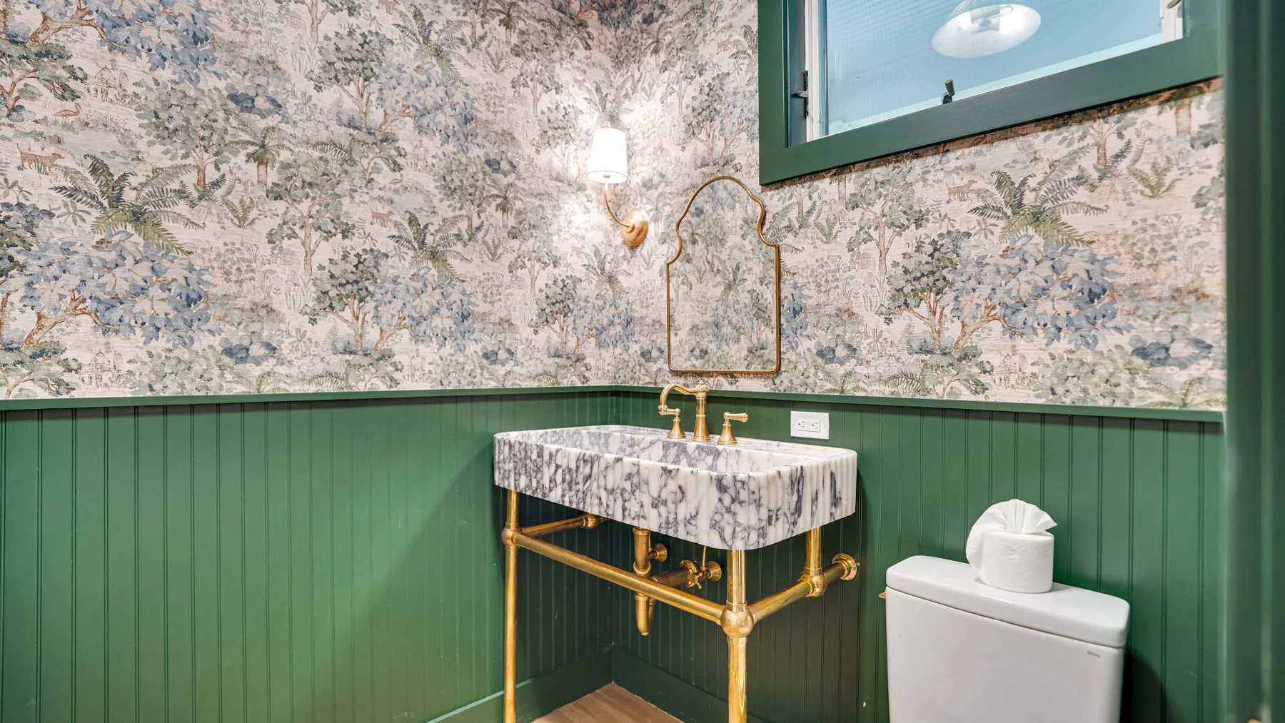 Un lavabo de baño con grifo dorado está junto a un inodoro.