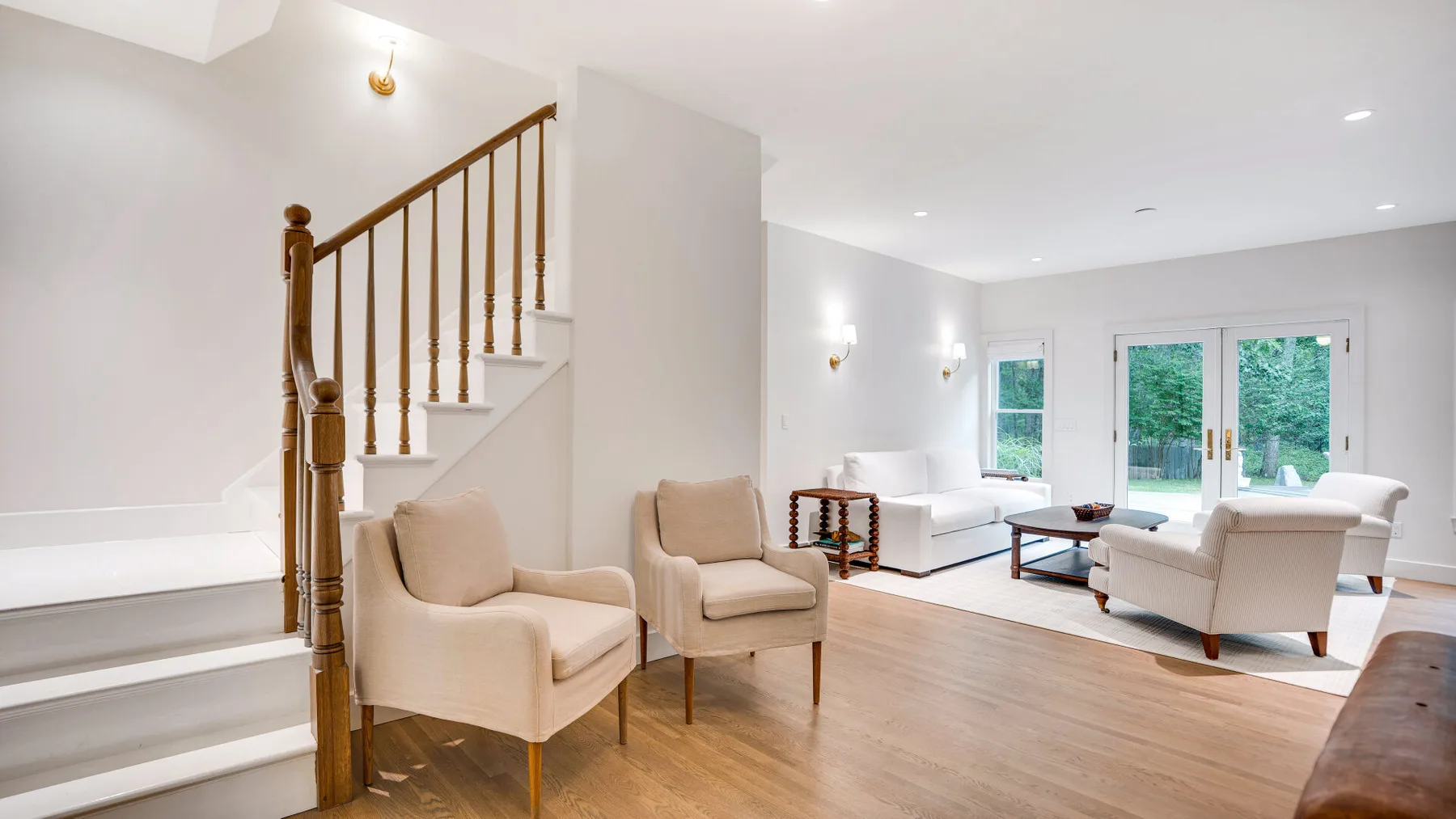 Una sala luminosa con asientos, una mesa de centro y una escalera.