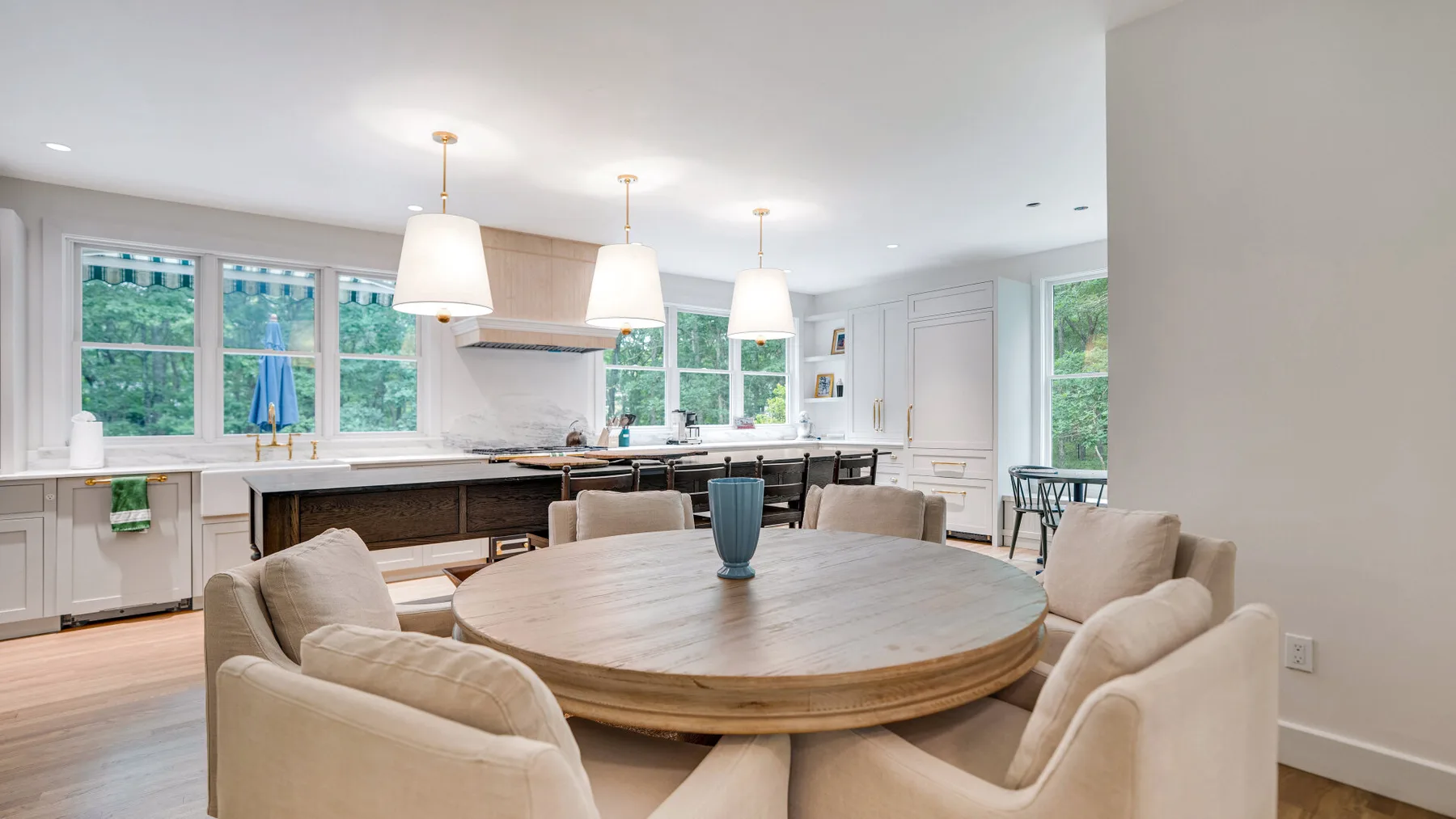Una cocina luminosa con zona de comedor, una mesa redonda grande y asientos alrededor.
