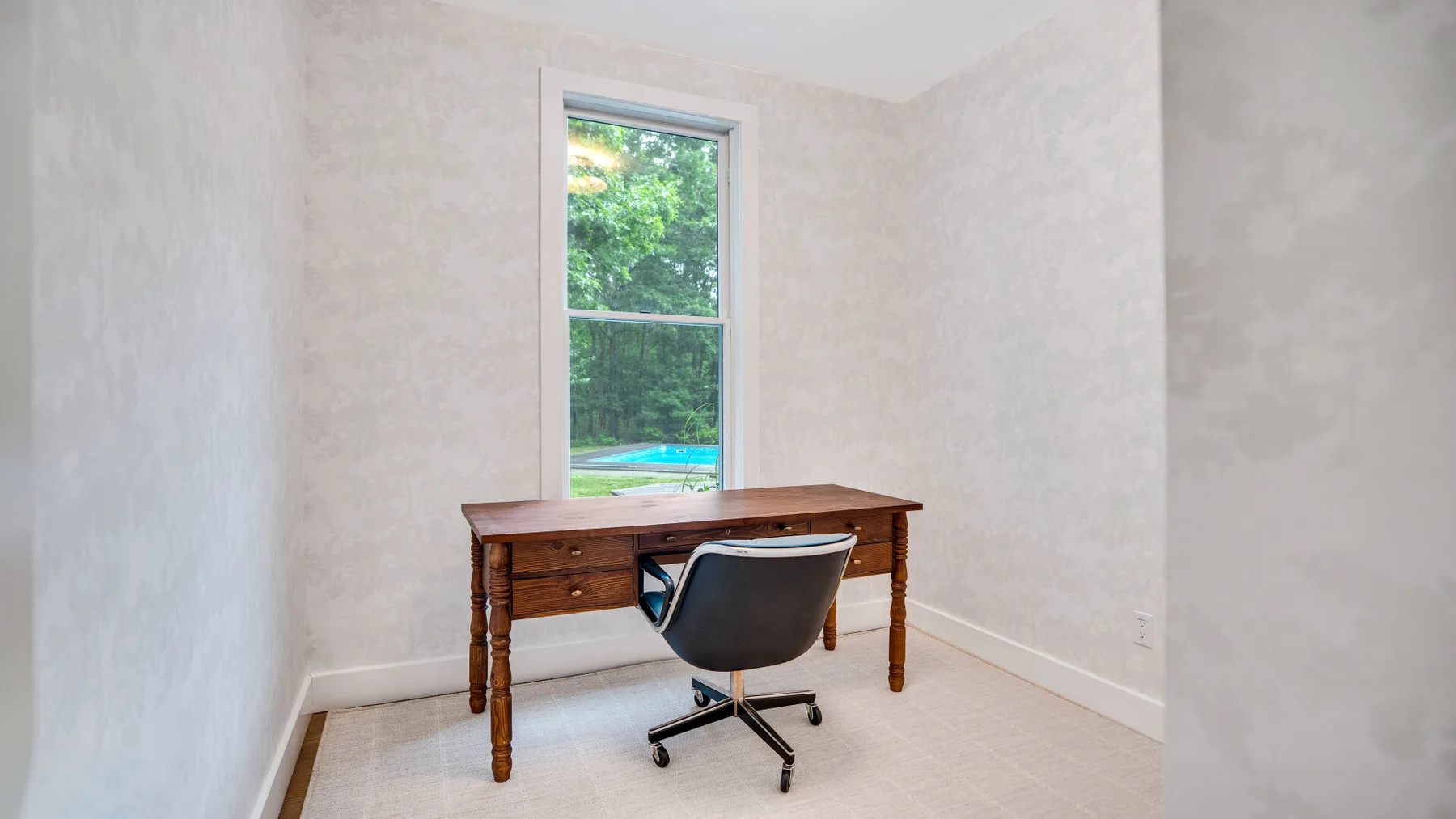 Una pequeña zona de estudio con escritorio de madera y silla junto a una ventana.