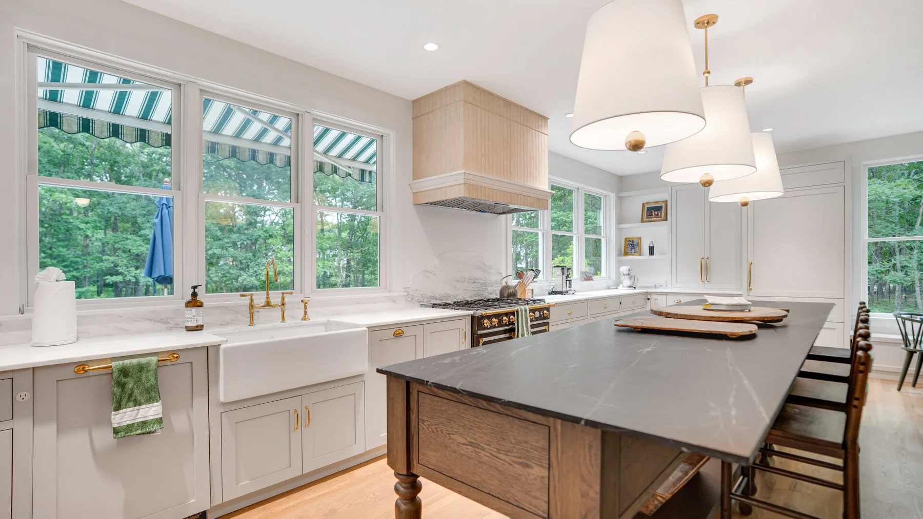 Una cocina luminosa con gabinetes blancos, grandes ventanas y una amplia isla central.