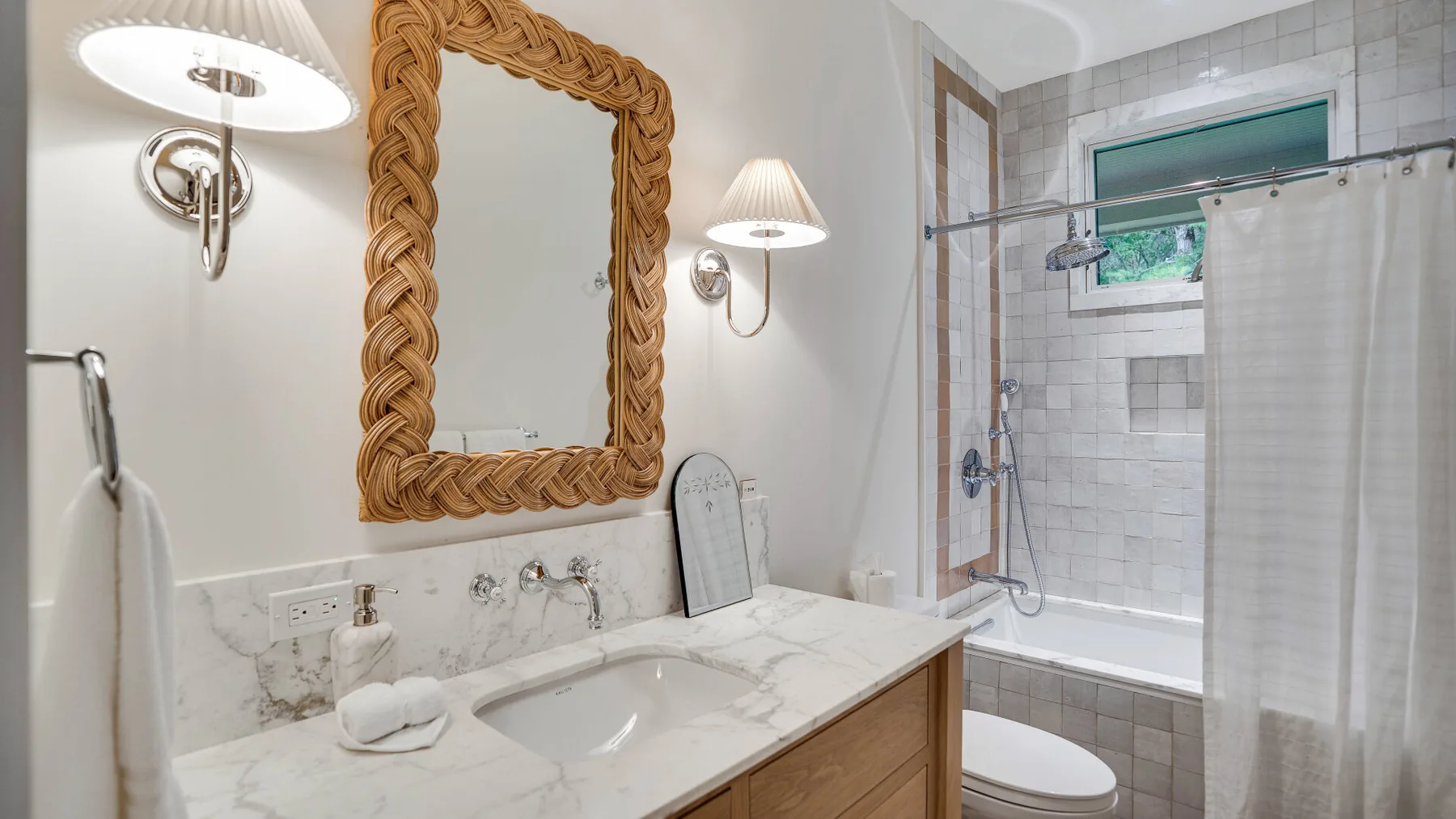 Un baño con un tocador de mármol y una ducha con mampara de vidrio.