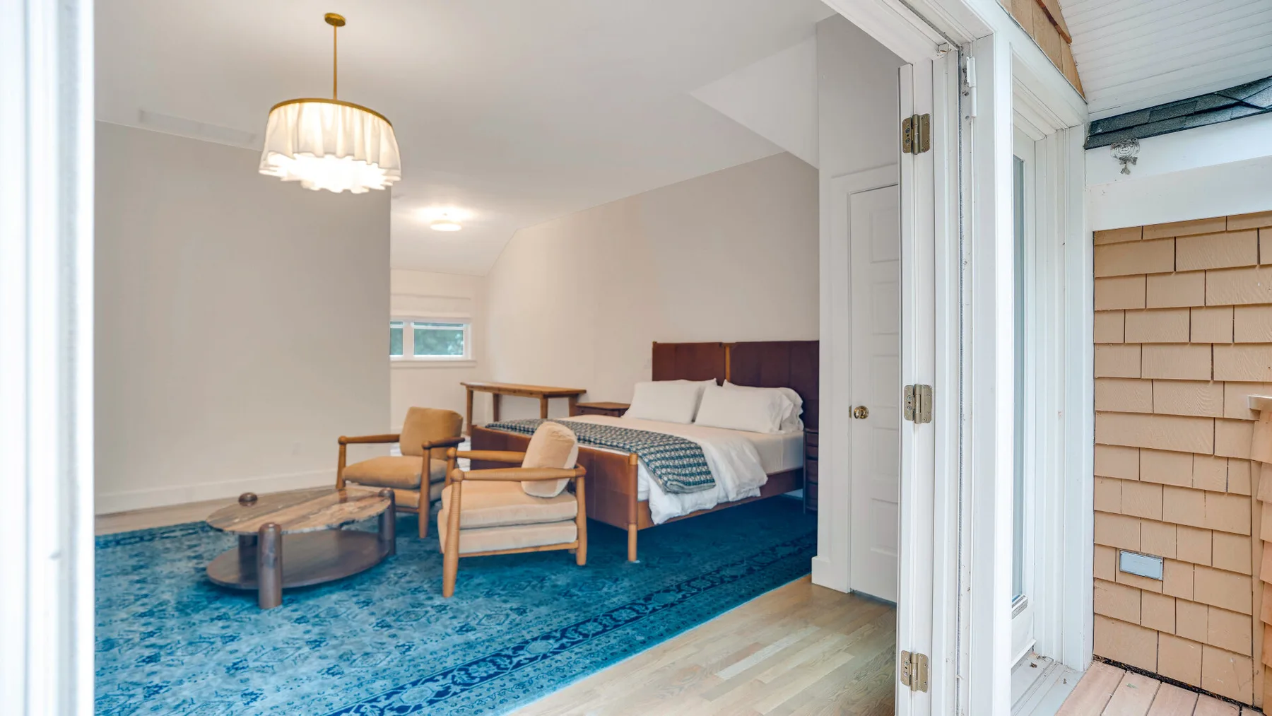 Un dormitorio con una cama y asientos dispuestos sobre una alfombra azul.