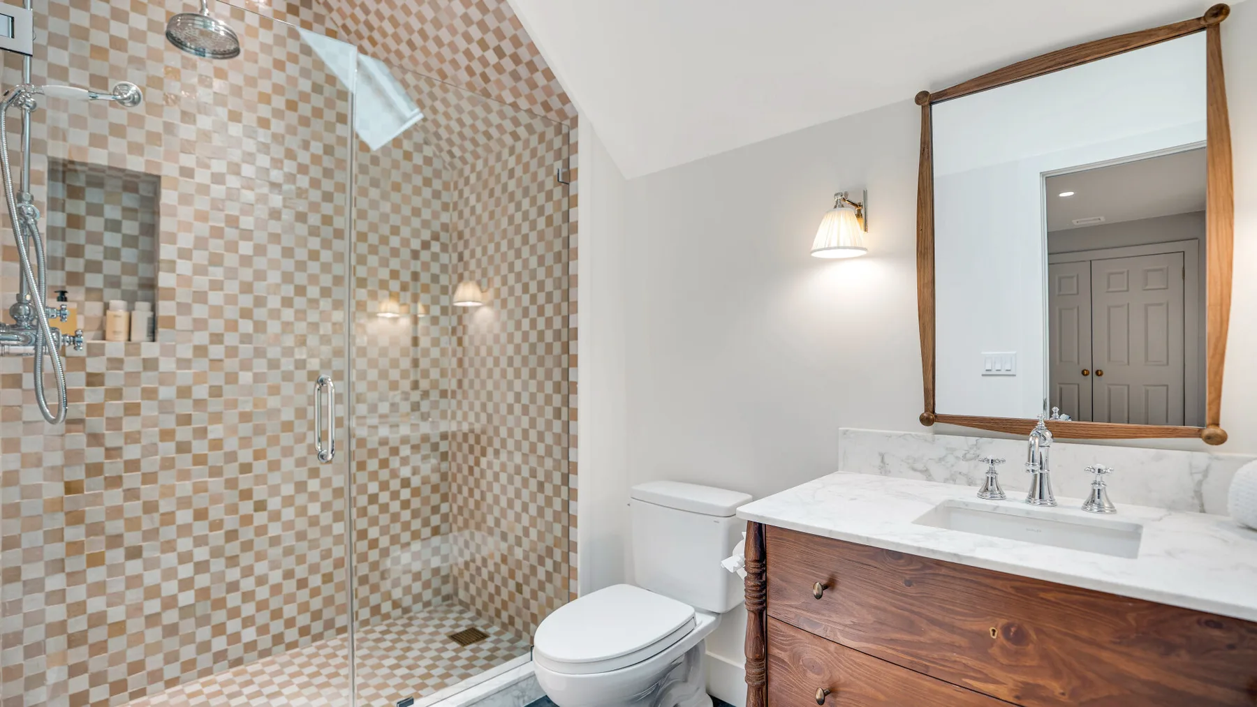 Baño con ducha de azulejos, inodoro y mueble de madera.