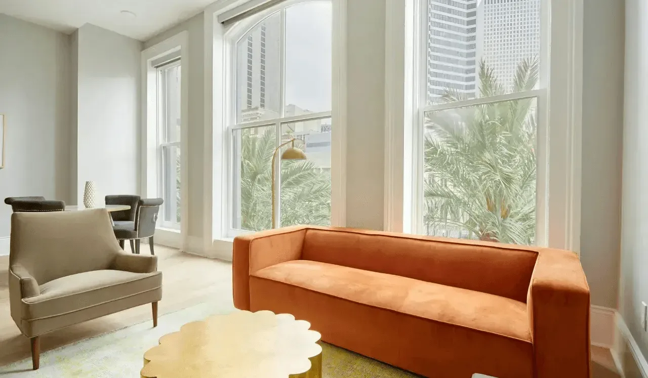 Una sala luminosa con asientos naranjas junto a ventanas altas.