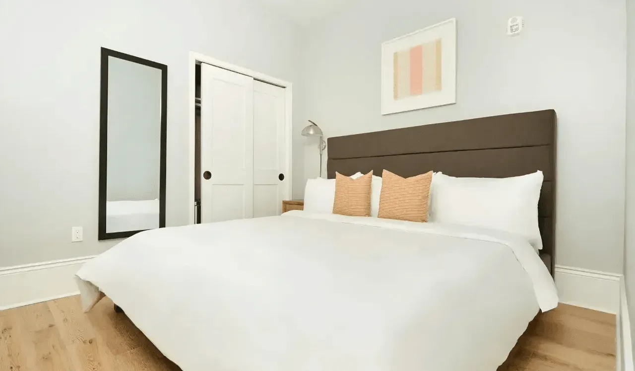 Un dormitorio con una cama bien arreglada y dos cojines decorativos a rayas.