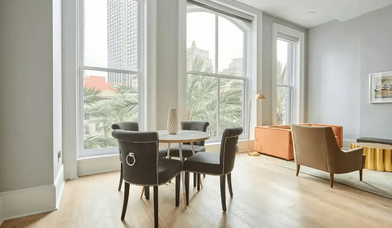 Una luminosa sala de estar tiene una mesa de comedor junto a grandes ventanas.