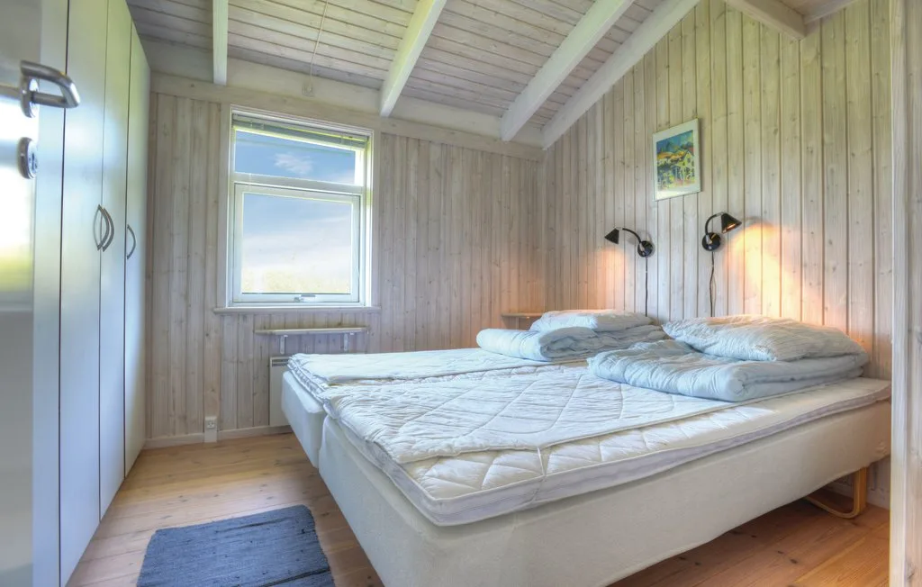 Un dormitorio con dos camas bajo un techo de madera inclinado y una ventana.