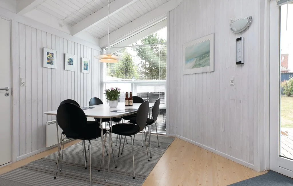Un comedor luminoso con una mesa y sillas junto a grandes ventanas.