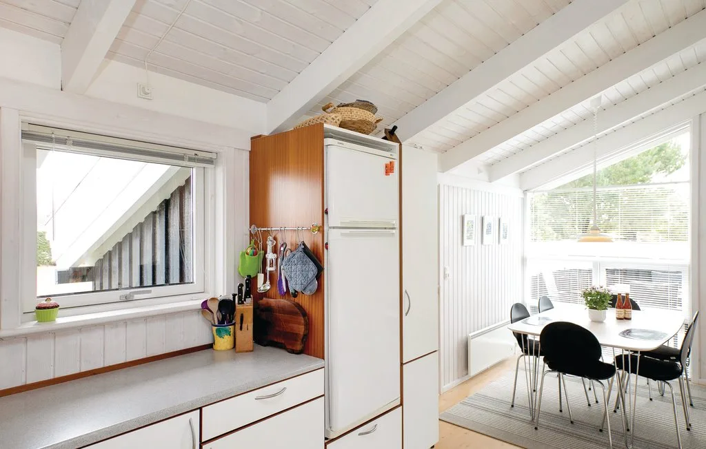 Una cocina luminosa se abre a un comedor con mesa y sillas.