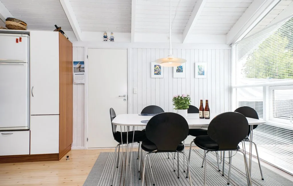 Un comedor luminoso con mesa, asientos y grandes ventanas.