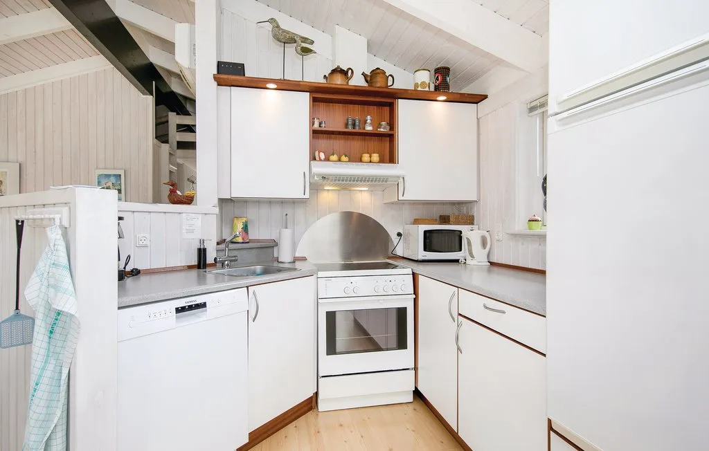 Una cocina luminosa con gabinetes blancos, una estufa y un microondas.