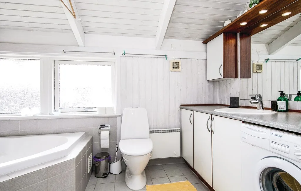 Un baño luminoso con bañera, inodoro y lavabo.