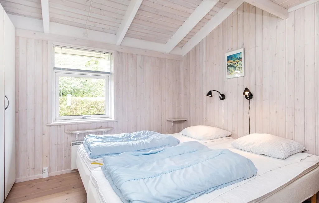 Un dormitorio con una cama vestida con ropa de cama azul claro y una ventana.