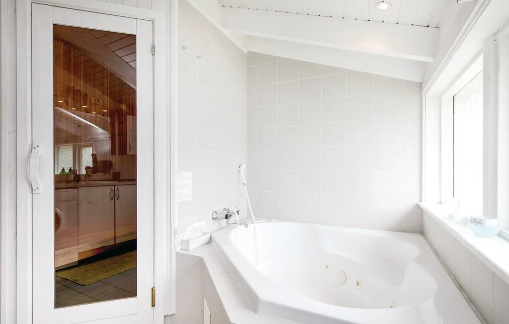 Un baño luminoso con una bañera grande junto a una ventana.