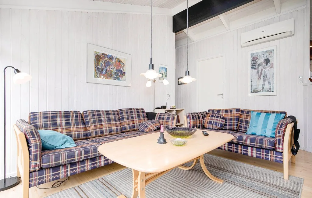 Una luminosa sala de estar con asientos a cuadros alrededor de una mesa baja de madera.