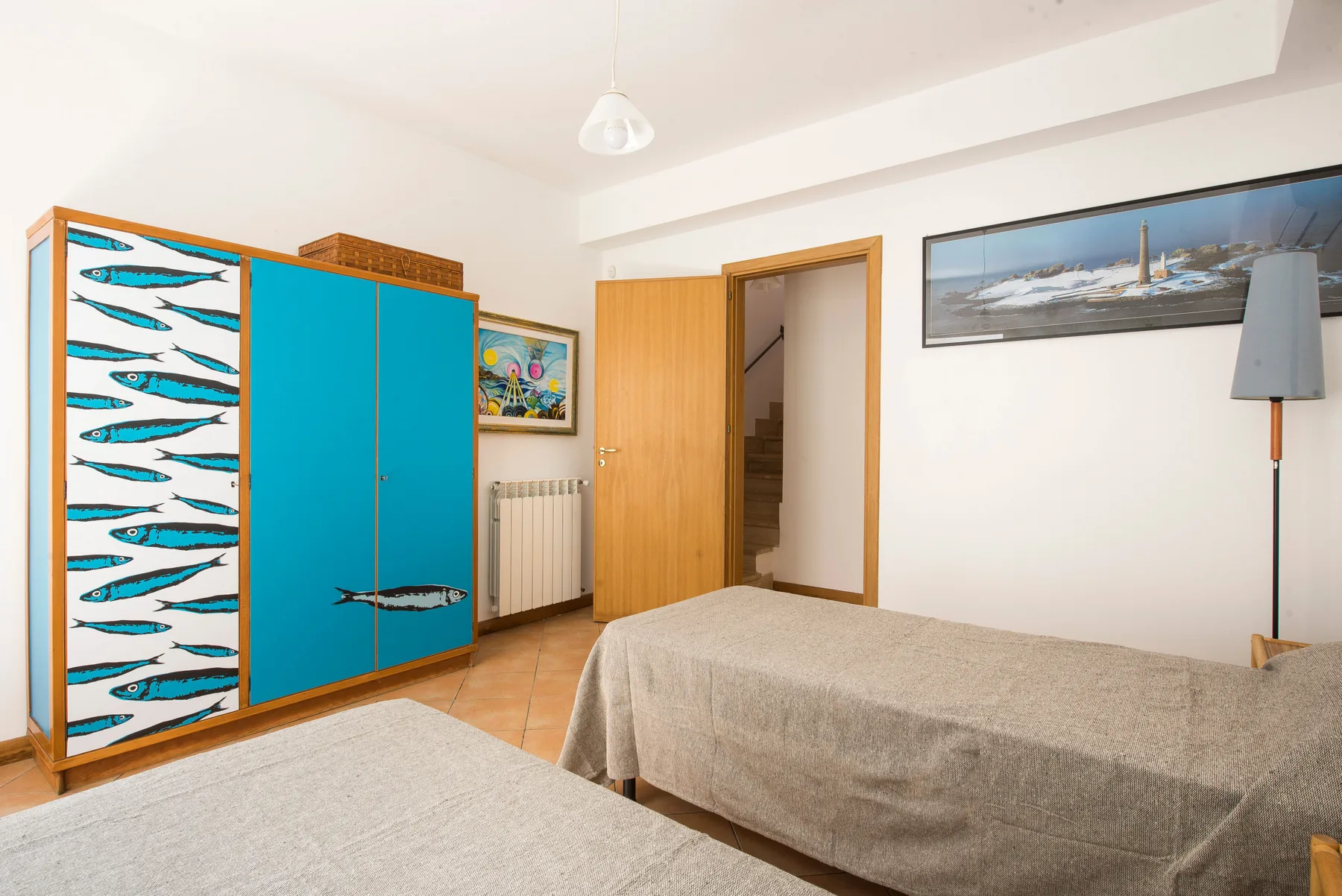 A bedroom with two beds and a turquoise wardrobe.
