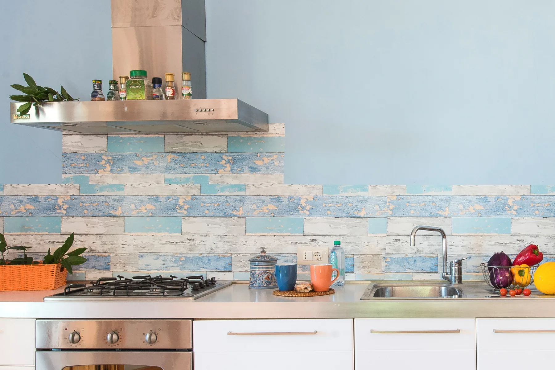 A kitchen with a gas cooktop, sink, and blue-and-white tiled backsplash.