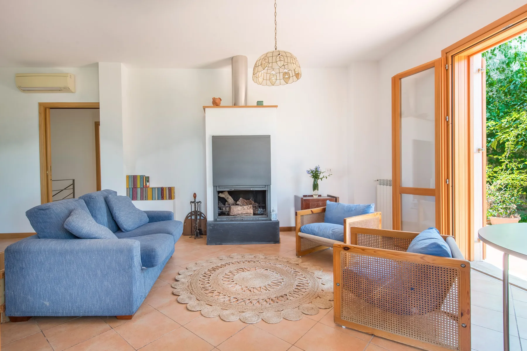 A bright living room with blue seating, a fireplace, and an open glass door.